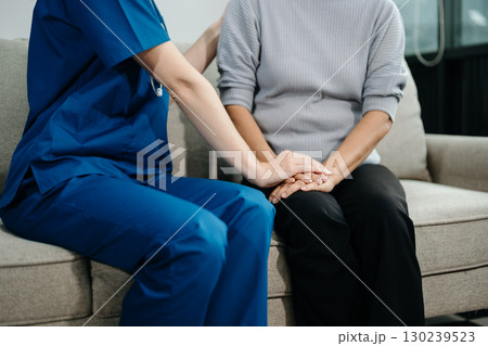 Doctors explain the use of medication to patients. Medical doctor holing senior patient's hands and comforting her on sofa 130239523