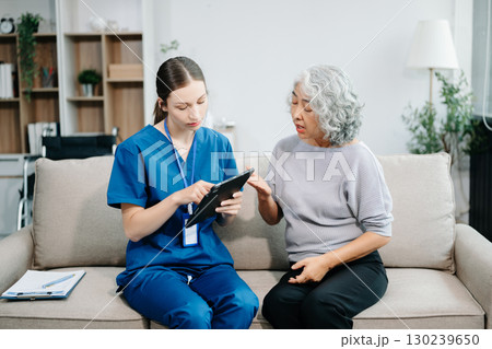Young nurse helping elderly woman walk in the room, holding his hand, supporting. Treatment and rehabilitation after injury Young nurse helping elderly woman walk in the room, holding his hand, supporting. Treatment and rehabilitation after injury 130239650