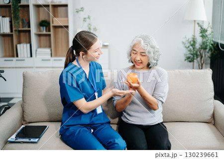 Caregiver doctor examine older patient use blood pressure gauge. woman therapist nurse at nursing home taking care of senior elderly woman sit on sofa. 130239661