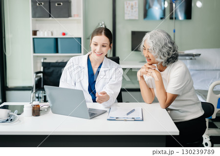 Doctor discussing treatment with male patient talking and laughing sitting on examination bed in clinic or hospital 130239789