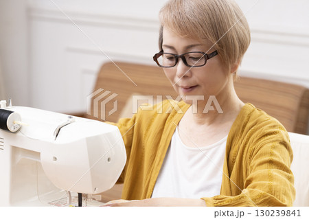 ミシンで洋服や小物を楽しそうに縫うシニア女性 130239841