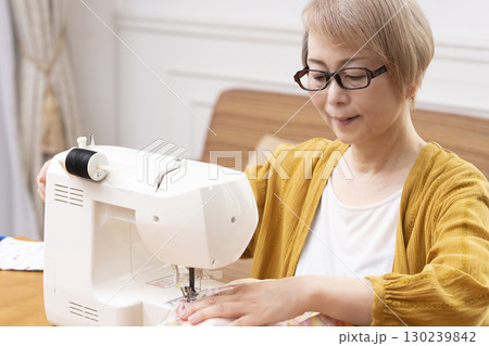 ミシンで洋服や小物を楽しそうに縫うシニア女性 ミシンで洋服や小物を楽しそうに縫うシニア女性 130239842