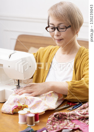 ミシンで洋服や小物を楽しそうに縫うシニア女性 ミシンで洋服や小物を楽しそうに縫うシニア女性 130239843