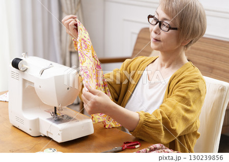 ミシンで洋服や小物を楽しそうに縫うシニア女性 130239856