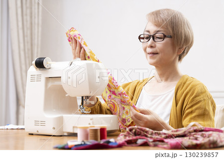 ミシンで洋服や小物を楽しそうに縫うシニア女性 130239857