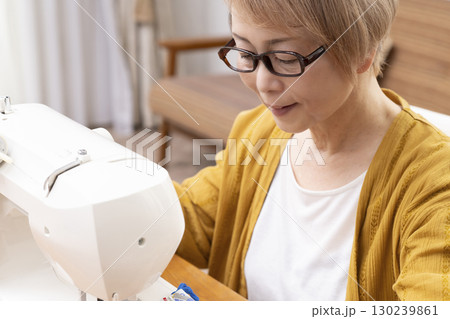 ミシンで洋服や小物を楽しそうに縫うシニア女性 130239861