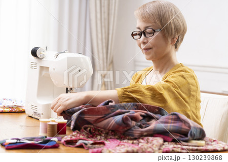 ミシンで洋服や小物を楽しそうに縫うシニア女性 130239868