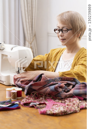 ミシンで洋服や小物を楽しそうに縫うシニア女性 130239869