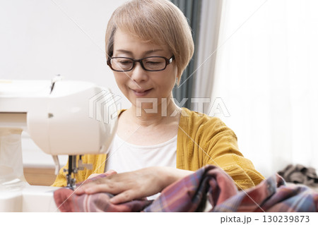 ミシンで洋服や小物を楽しそうに縫うシニア女性 ミシンで洋服や小物を楽しそうに縫うシニア女性 130239873