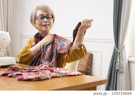ミシンで洋服や小物を楽しそうに縫うシニア女性 130239884