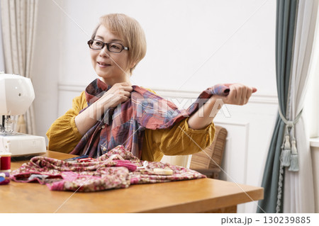 ミシンで洋服や小物を楽しそうに縫うシニア女性 130239885