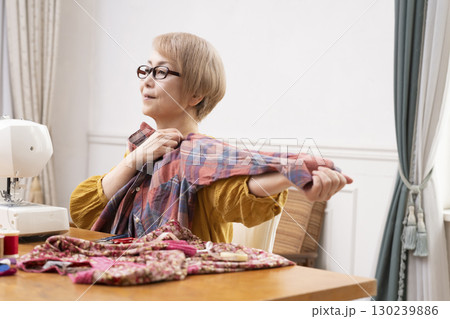 ミシンで洋服や小物を楽しそうに縫うシニア女性 130239886