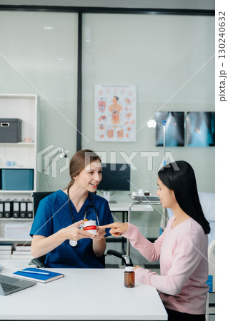 Doctor discussing treatment with Female patient talks to discuss results or symptoms and sitting on examination desk 130240632