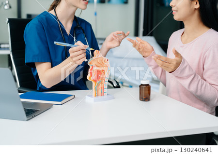 Doctor discussing treatment with Female patient talks to discuss results or symptoms and sitting on examination desk 130240641