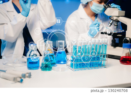 Young scientists conducting research investigations in a medical laboratory, a researcher in the foreground is using a microscope in laboratory Young scientists conducting research investigations in a medical laboratory, a researcher in the foreground is using a microscope in laboratory 130240708