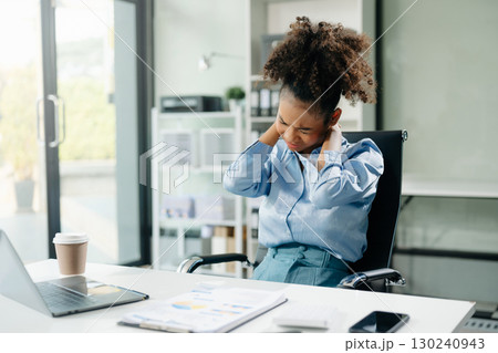 Overworked young Asian businesswoman office worker suffering from neck pain after had a long day at her office desk 130240943