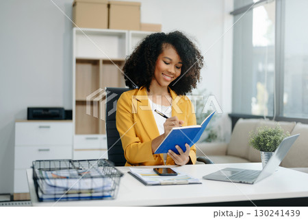 Confident woman with a smile standing holding notepad and tablet Confident woman with a smile standing holding notepad and tablet 130241439