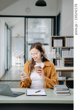 Confident woman with a smile standing holding notepad and tablet at the office. 130242176