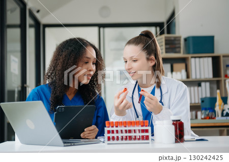 Doctor Talks With Professional Head Nurse or Surgeon, They Use Digital tablet Computer. Diverse Team of Health Care Specialists Discussing Test Result 130242425