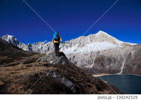 Backpacking woman hiking on high altitude mountain top 130242529