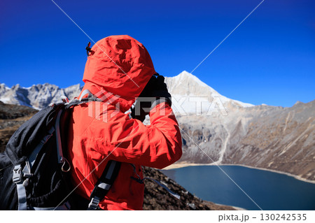 Backpacking woman photographer taking picture on high altitude mountain top Backpacking woman photographer taking picture on high altitude mountain top 130242535