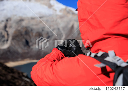 Backpacking woman set the sports watch on high altitude mountain top 130242537