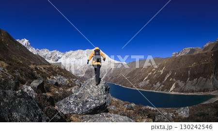 Backpacking woman hiking on high altitude mountain top 130242546