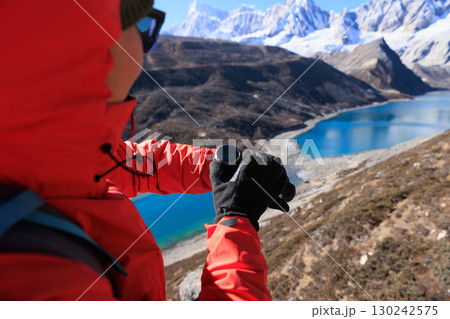 Backpacking woman checking the elevation on sports watch on high altitude mountain top 130242575