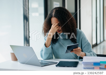 Woman who is tired and overthinking from working with tablet and laptop at modern office. Woman who is tired and overthinking from working with tablet and laptop at modern office. 130242597