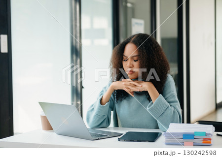 Woman who is tired and overthinking from working with tablet and laptop at modern office. 130242598