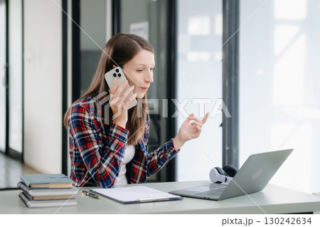 Beautiful woman using laptop and tablet while sitting at her working place. Concentrated 130242634
