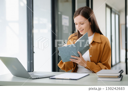 Businesswoman working in the office with working notepad, tablet and laptop documents Businesswoman working in the office with working notepad, tablet and laptop documents 130242683