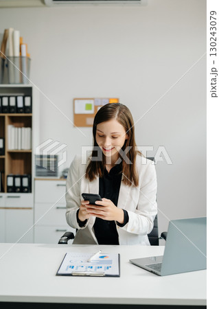 Confident business expert attractive smiling young woman typing laptop and holding digital tablet Confident business expert attractive smiling young woman typing laptop and holding digital tablet 130243079