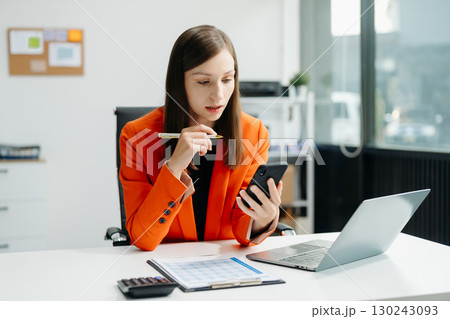Confident business expert attractive smiling young woman typing laptop and holding digital tablet 130243093