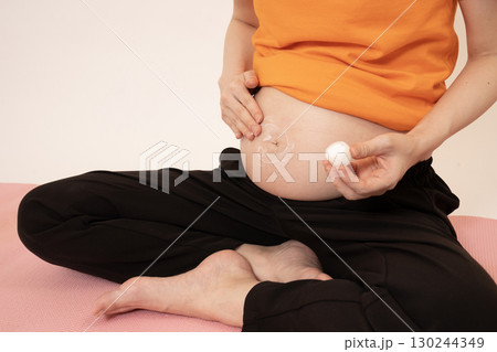 妊娠8ヶ月のお腹にクリームを塗る女性 130244349