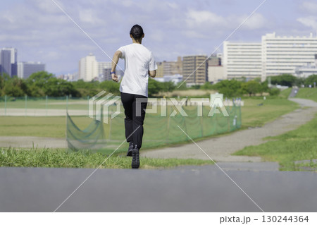 多摩川の土手をランニングする若い男性の後ろ姿 130244364