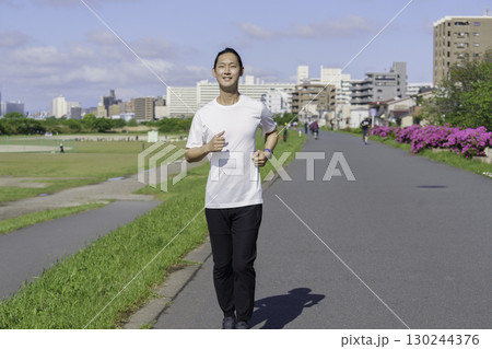 多摩川の土手をランニングする若い男性 130244376