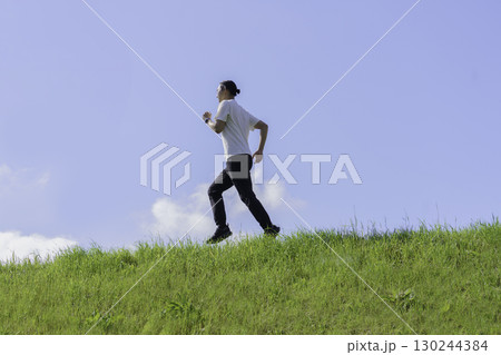 多摩川の土手をランニングする若い男性 多摩川の土手をランニングする若い男性 130244384