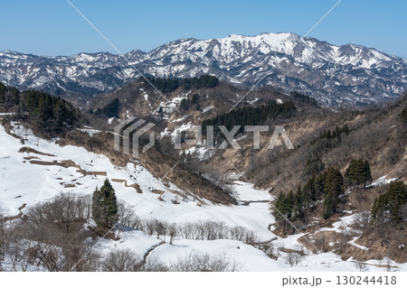 雪の残る棚田と雪化粧した山々 130244418