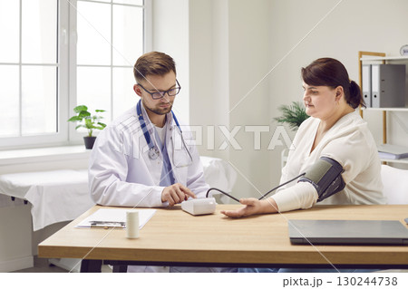 Doctor uses sphygmomanometer to check blood pressure of young overweight woman patient Doctor uses sphygmomanometer to check blood pressure of young overweight woman patient 130244738