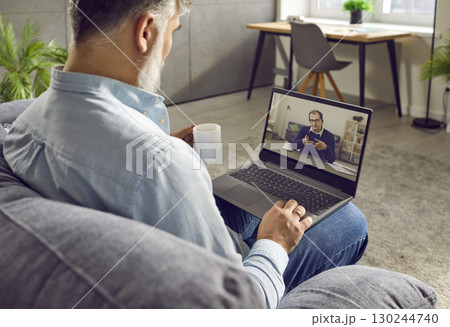 Rear view of businessman talking with colleague using laptop webcam Rear view of businessman talking with colleague using laptop webcam 130244740
