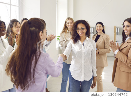 Team of happy diverse business women showing recognition to their young colleague 130244742