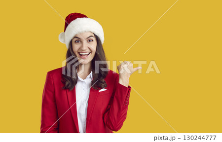 Happy woman advertises Christmas sale and points to copy space on yellow background Happy woman advertises Christmas sale and points to copy space on yellow background 130244777