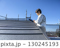 戸建て家屋の屋根修繕工事進行状況を確認する男性 130245193