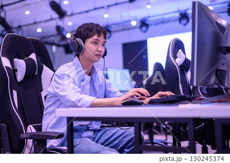 　ゲーミングチェアでゲームに没頭する男子学生の後ろ姿 130245374