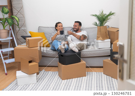 young couple shares joyful cheers on the sofa, surrounded by unpacked boxes, sipping coffee as they make their new house a home during the move young couple shares joyful cheers on the sofa, surrounded by unpacked boxes, sipping coffee as they make their new house a home during the move 130246781