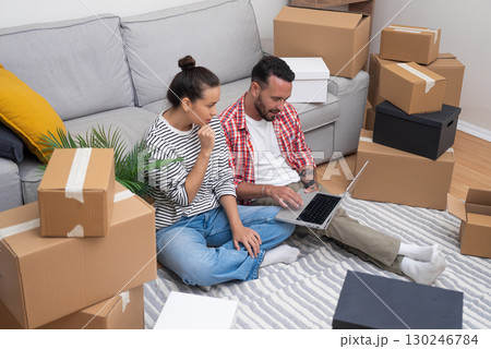 Moving Forward: Couple in a fresh home, laptop in hand, explores online decor options, shaping their dream home, or planning their move Moving Forward: Couple in a fresh home, laptop in hand, explores online decor options, shaping their dream home, or planning their move 130246784