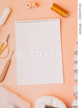 Blank notebook with sewing tools on peach background 130247419