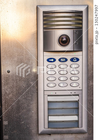 Modern metal intercom with keypad and camera mounted on building entrance Modern metal intercom with keypad and camera mounted on building entrance 130247997