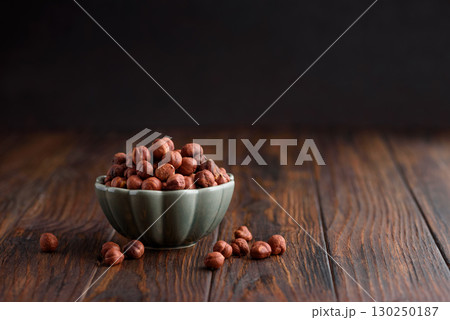 Hazelnuts in a bowl on a dark wooden background. Front view Hazelnuts in a bowl on a dark wooden background. Front view 130250187